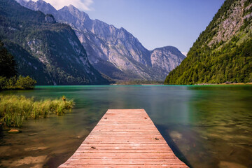 Langzeitbelichtung von einem Steg an dem See Königssee mit Bergen / Alpen im Hintergrund