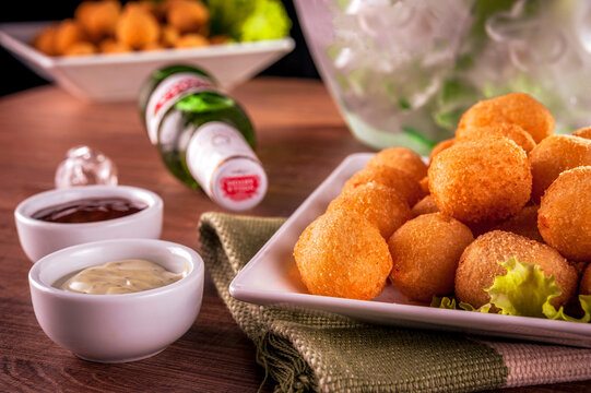 Curitiba, Parana, Brazil - 11, 19, 2019: A portion of deep fried cheese croquette and sauce with Stella Artois bottle  and a bucket of ice in background - Bolinha de queijo