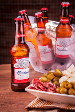 Curitiba, Parana, Brazil - 11, 19, 2019: A budweiser bottle with a portion of cold cuts and a bucket of ice with budweiser bottles in background