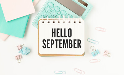 written hello september text on notepad with keyboard on table