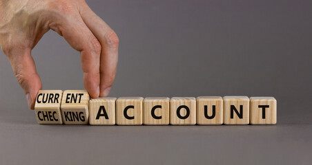 Current or checking account symbol. Businessman turns wooden cubes and changes words 'checking account' to 'current account'. Beautiful grey background, copy space. Business concept.