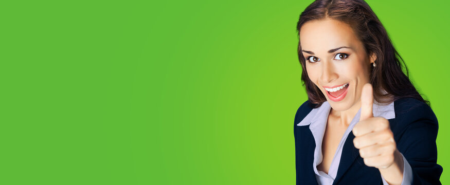 Businesswoman in confident black suit, showing thumbs up gesture, copy space place for some text, advertising or slogan, over green color background. Business concept photo.