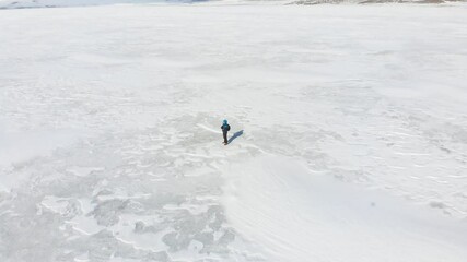 Aerial cinematic view male person stands in middle white snow field thoughtful admiring nature. Concept of well being and creative process