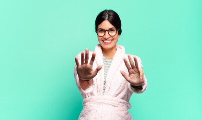 young pretty woman smiling and looking friendly, showing number nine or ninth with hand forward,...