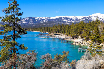 a stunning shot of the deep blue lake water with wooden boat docks on the lake and lush green pine...
