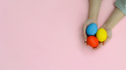 Happy Easter day. Eggs in the hands of a small child on a pink background.Preparation for the spring holiday.A greeting card or banner for a website or store sale.Copy space.Flat lay.Mock up