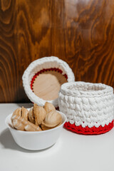 Knitted baskets on the table for food. Handmade kitchen decor. Large color threads for knitting decorative elements. Sweets and cookies on a white table closeup.