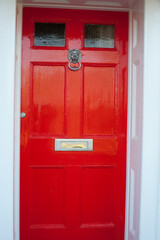 close-up of a freshly painted bright red front door with Lion head door knocker