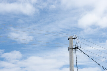 Power line post with with white insulators and wires on a background of blue sky with clouds