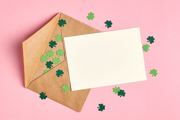 Saint Patricks day invitation card mockup with envelope, green paper shamrock on pink background