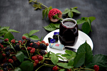 .Homemade Blackberry Jam in a Glass Jar on White Plate Decorated with Fresh Blackberry Branches