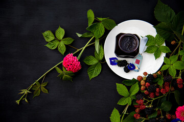 Homemade Blackberry Jam in a Glass Jar on White Plate Decorated with Fresh Blackberry Branches