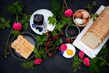 Breakfast Set Up with Toasted, Homemade Organic Blackberry Jam, Hard boiled eggs, and Fried egg on Black Background