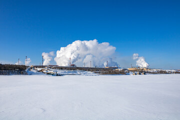 A large industrial complex against the backdrop of a bright blue sky.