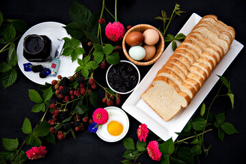 Breakfast Set Up with Homemade Organic Blackberry Jam, bread, Hard boiled eggs, and Fried egg decorated with fresh black berries
