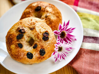 Homemade Cinnamon Raisin Bagels on Plaid Napkin and Wood Background.