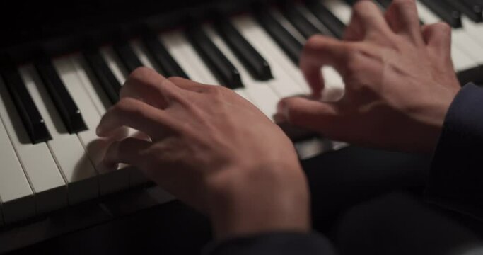 Close up of musician hands playing bass guitar neck in dark studio background.