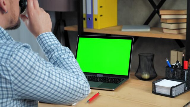 Businessman at home office looks display green screen mock up chroma key laptop computer listen watching distance remote online video business webinar master class course lesson drinking coffee tea