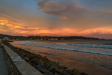 Obraz premium great golden sunrise on the beach of Hendaye, French Basque country, in the foreground the promenade and the beach and Hondarribi 
