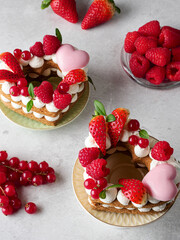 The heart-shaped layer cake is decorated with fresh berries, chocolate and flowers. Cake with fresh strawberries, raspberries and red currants. Dessert with red berries. Copy space.  Valentine's Day.
