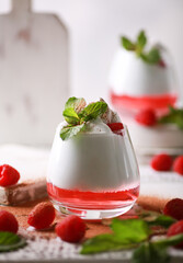 Creamy dessert with raspberry jelly in a clear glass, with mint, berries and cocoa sprinkles on a...
