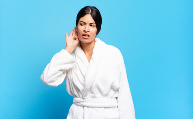 young hispanic woman looking serious and curious, listening, trying to hear a secret conversation...
