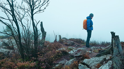 Outdoor Wanderer Frau mit Rucksack und dicker Kleidung im Nebel auf Felsvorsprung schroffe karge...