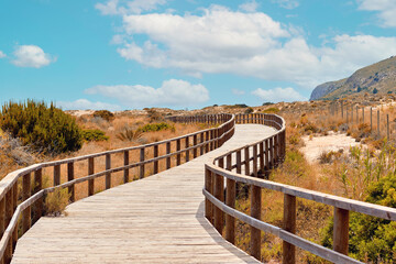 Fototapeta na wymiar Wooden boardwalk leading through sandy dunes to Sea. Spain