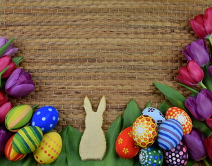 tulips, painted eggs and bunny shaped cookies on brown background