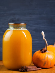 A jar of homemade pumpkin juice on the table and fresh pumpkins