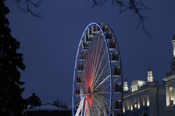 Ferris wheel on the background of an old building in the evening