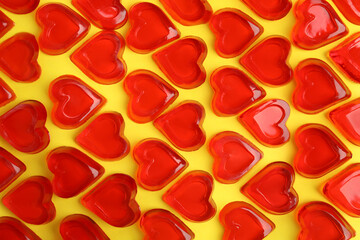 Sweet heart shaped jelly candies on yellow background, flat lay