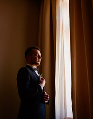 Wedding morning groom in an expensive interior. Happy groom on his wedding day. The groom is dressed at home. Preparation of groom before wedding at home.