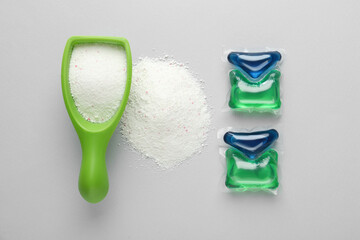 Laundry capsules and detergent powder on light grey background, flat lay