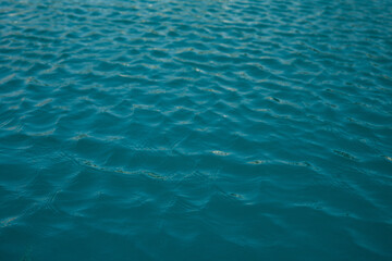 Fototapeta na wymiar The texture of clear blue water with small waves on a sunny day. Peace and tranquility. Background