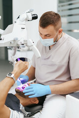 Young man with patient bib on a dental chair and a dentist who sits next to him. He looks on his...