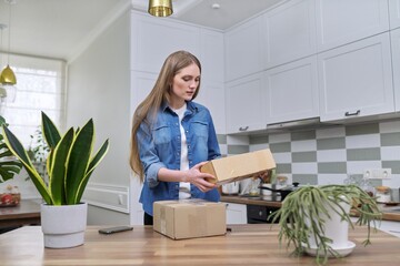 Young happy woman unpacking cardboard boxes, unboxing expected postal parcel