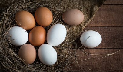 brown and white eggs in a sleepy nest on a brown wooden background with burlap
