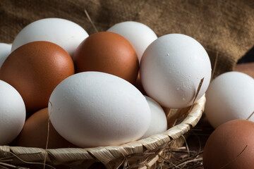 wicker wooden plate with brown and white eggs on a background of burlap