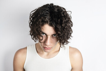 Portrait of a teenage boy with an aggressive sad look, the guy has problems communicating with peers. Portrait of a handsome charismatic teenage boy with curly hair