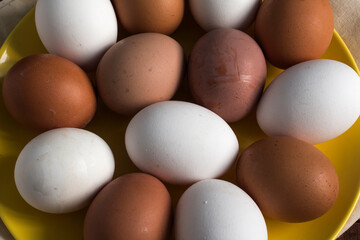 yellow plate with eggs of different colors, close-up view from above