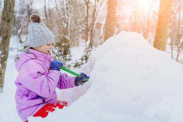 Children build snowman. Kid building snow house playing outdoors on snowy winter day. Girl play with snow. Warm winter clothing for walking.