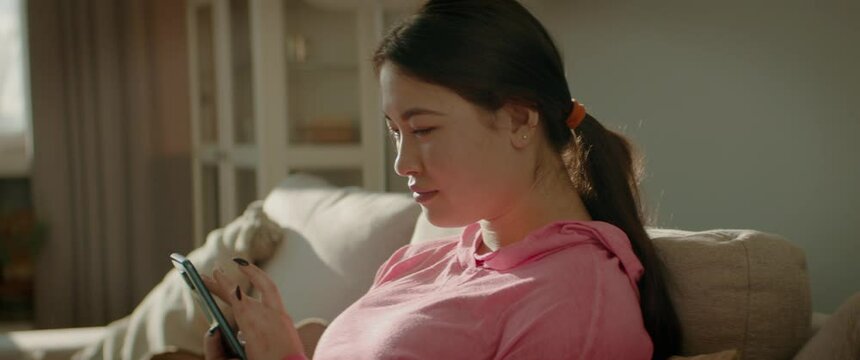 MID Portrait Asian Korean female checking her phone at home early in the morning. Natural cinematic light. Shot with 2x anamorphic lens