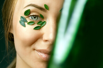 Closeup of young woman`s face with boxwood leaf patches. Spa and wellness concept template banner for design. Cosmetic product advertising