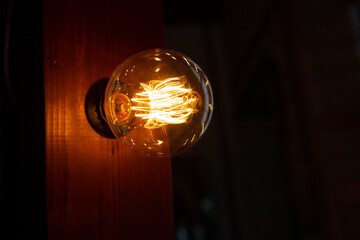 Old glowing light bulbs on dark background.Bright glowing clear glass lamp pear shaped close up....