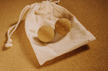 Close up of fascia release cork massage balls on a organic cotton bag on a cork mat background, with warm golden light. Concept: eco friendly and sustainable self care tools, props.