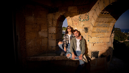 Couple  sitting inside old castle on a rock bench 