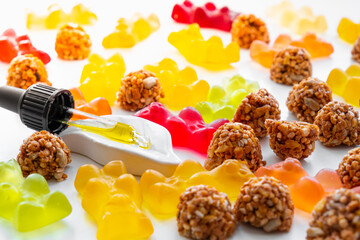 Gummy bears, cbd cookies and thd oil dropper in white backdrop. THD or cannabis sweets in form of...