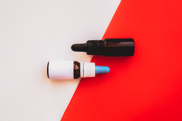 Two bottles with dropper against vibrant white and red backdrop. Essential, cbd or thd oils in tiny bottles, copy space background