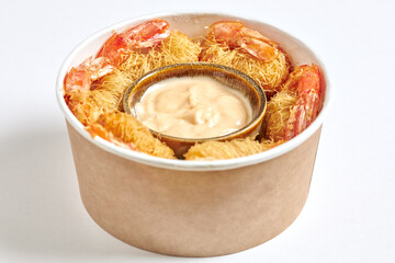 Close-up of a cube of fried prawns wrapped in Kataifi pasta and served with dragon sauce.